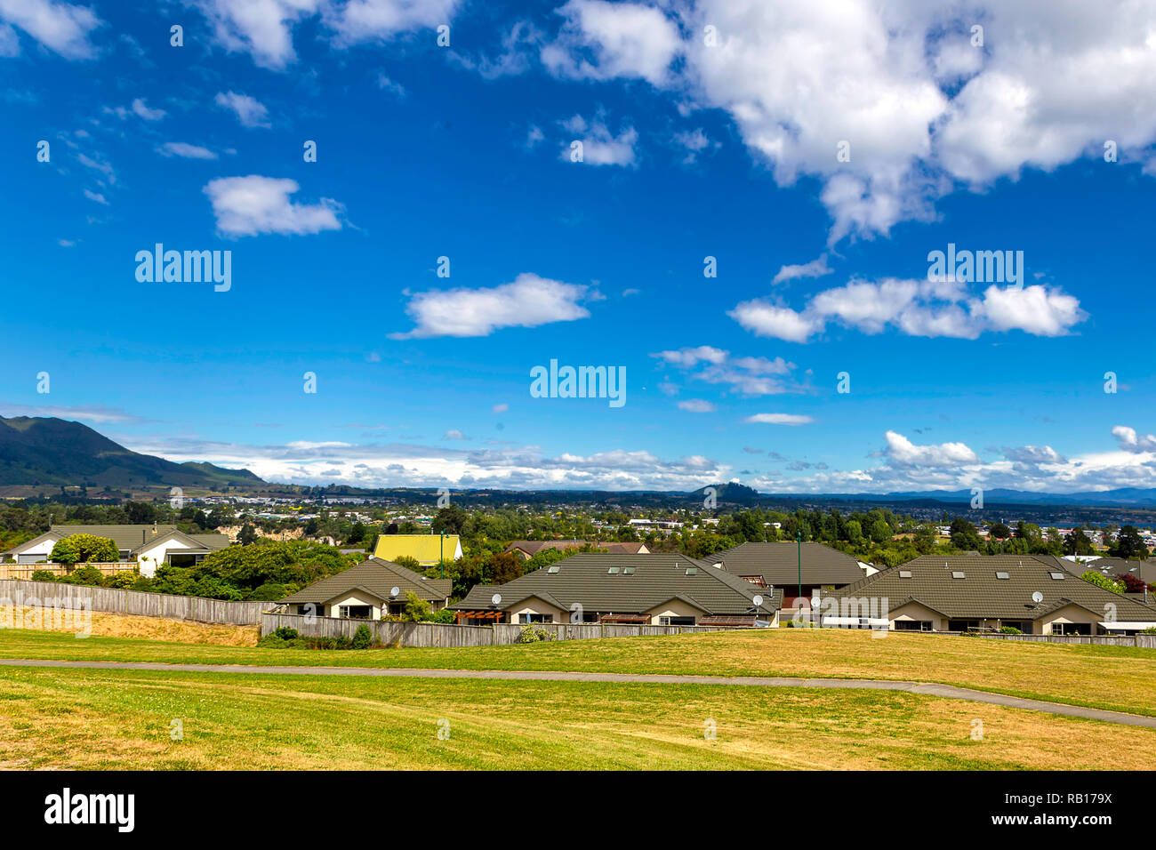 Green and yellow grass lawn, roofs of the houses and the view of Taupo town in New Zealand Stock Photo
