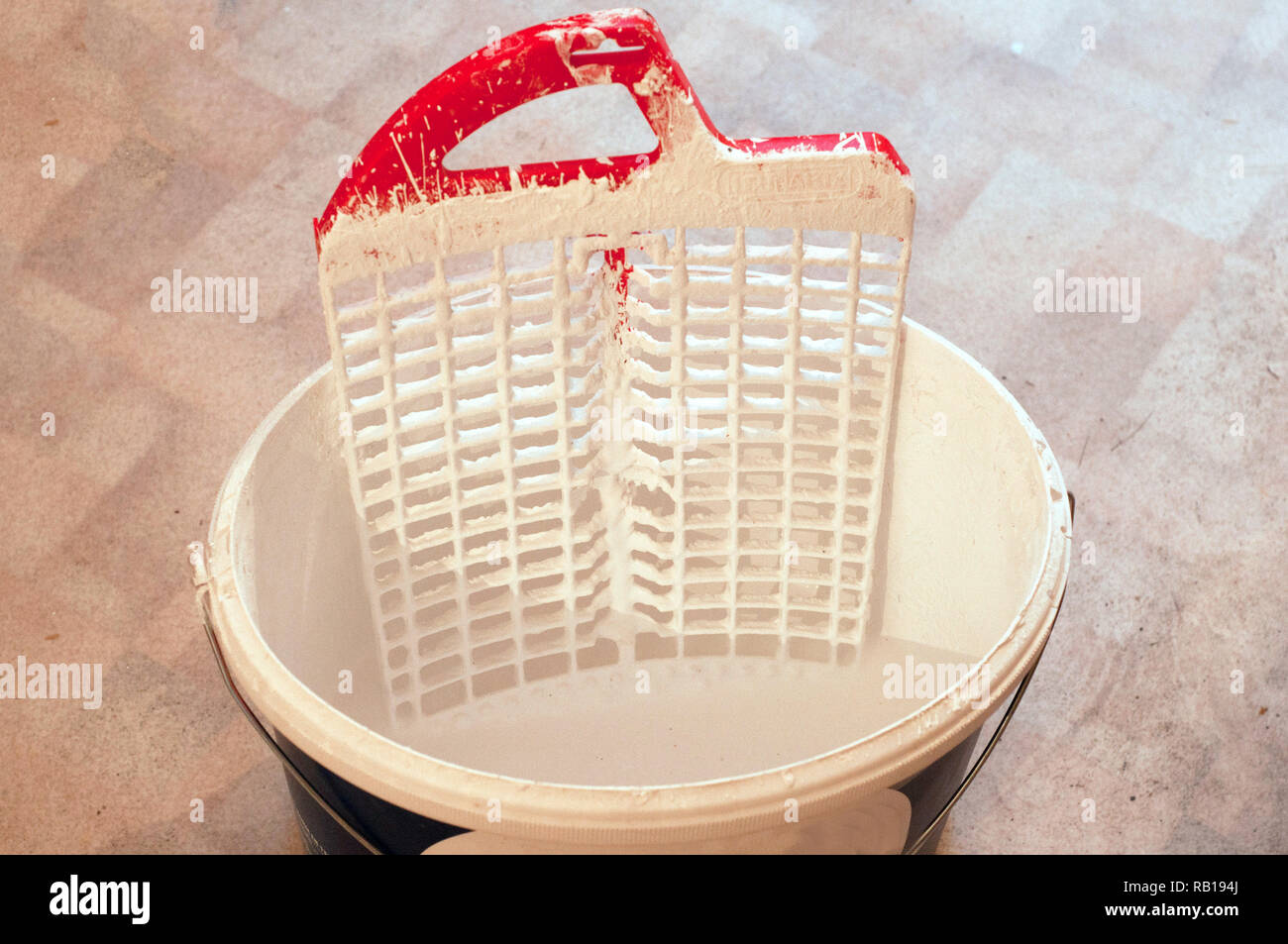 A bucket with white water emulsion paint with paint trays on the pvc