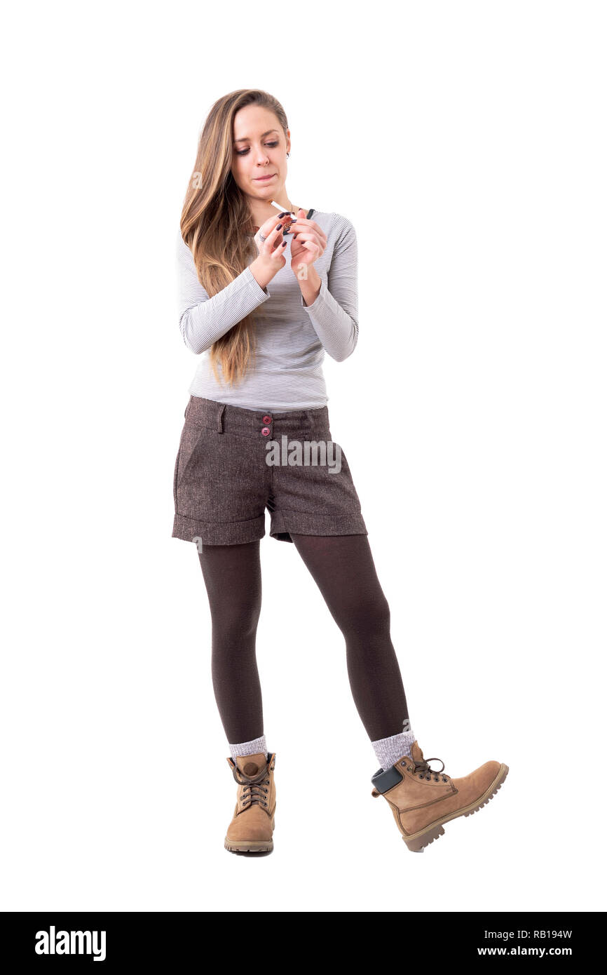 Candid unposed blonde young stylish woman rolling cigarettes. Full body  isolated on white background Stock Photo