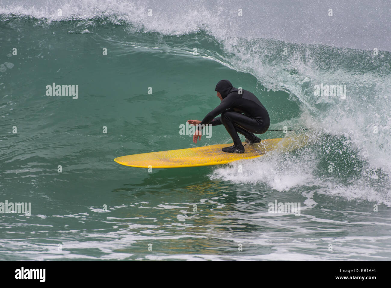 Skilled surfer in black wetsuit crouches to fit into the tube of a