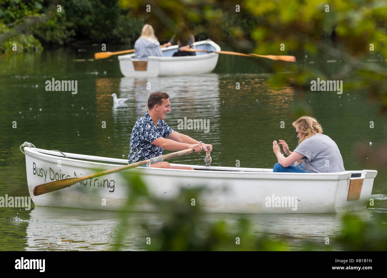 A young couple in a rowing boat at a boating lake in Summer, in