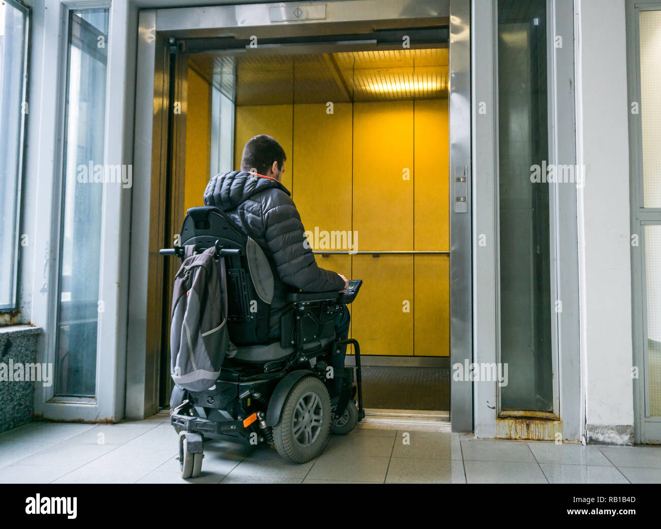 Handicapped male on wheelchair going in elevator Stock Photo