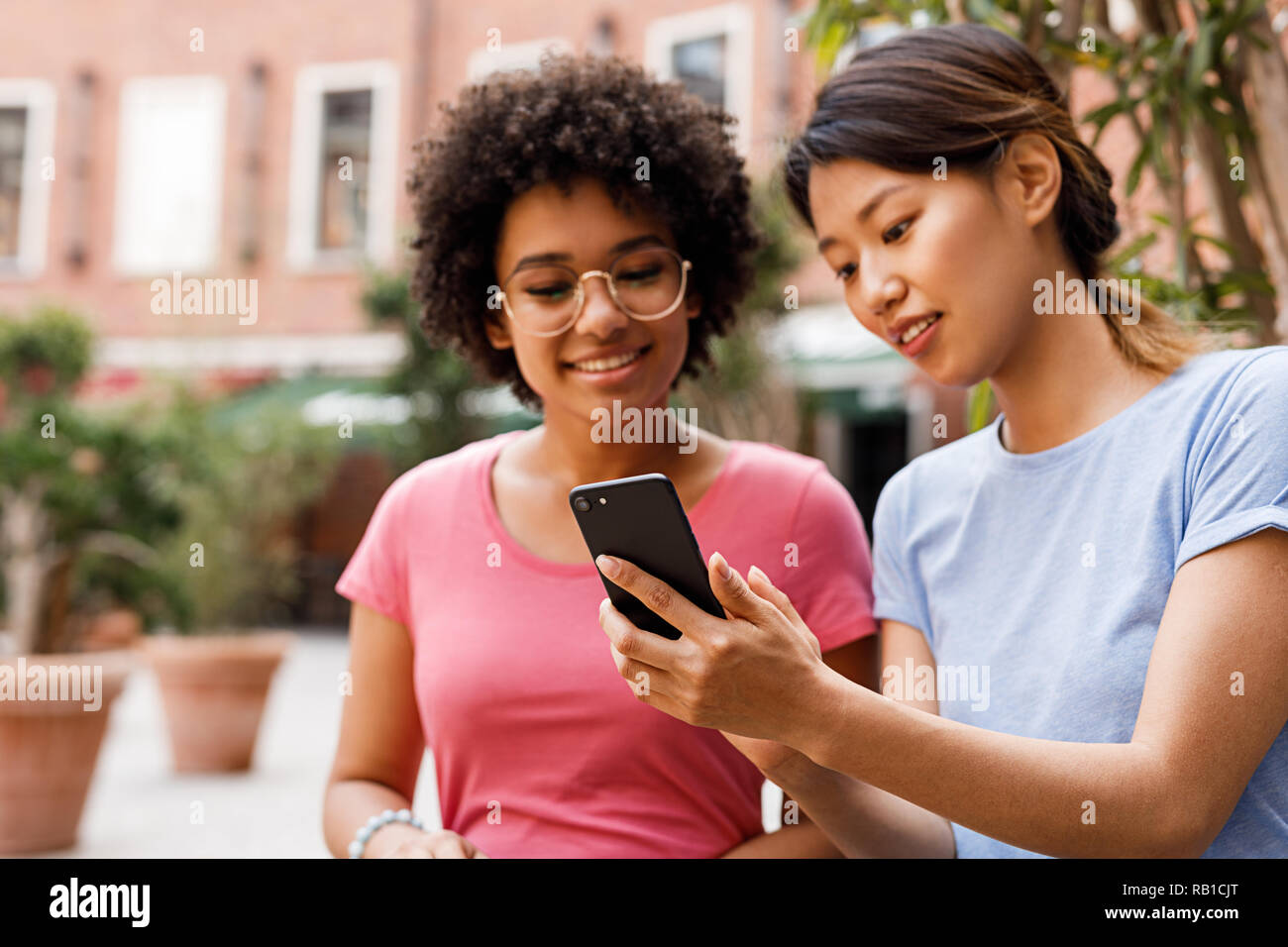 Two female friends looking at smartphone and talking Stock Photo