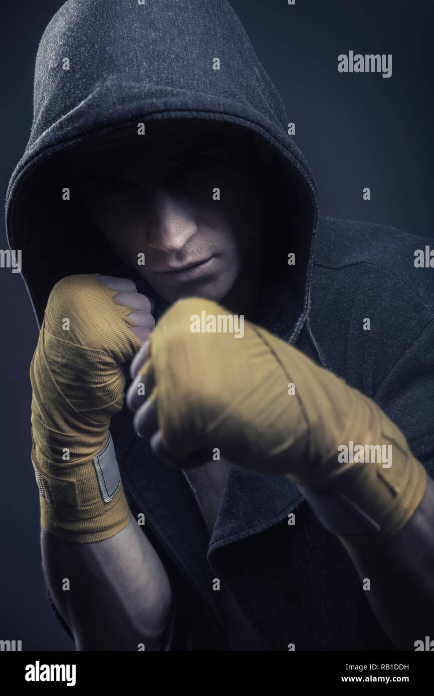 Martial arts fighter in the hood over black background Stock Photo