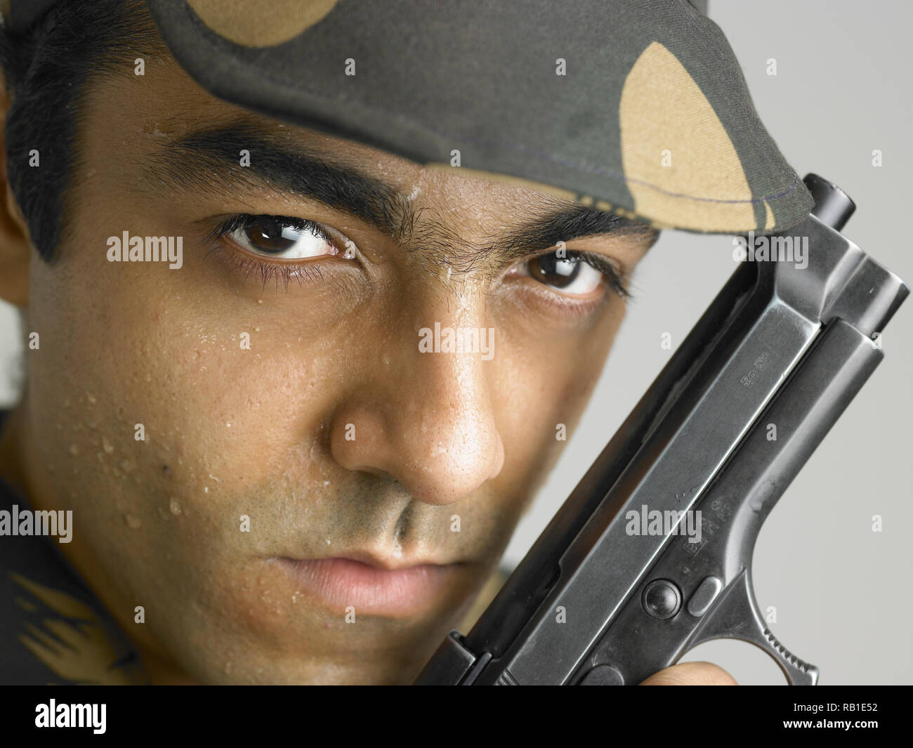 PORTRAIT OF INDIAN SOLDIER DRESSED IN UNIFORM HOLDING A HAND GUN Stock portrait-of-indian-soldier-dressed-in-uniform-holding-a-hand-gun-stock