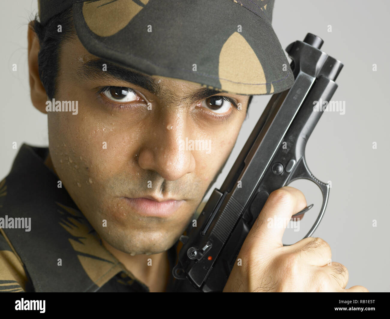 PORTRAIT OF INDIAN SOLDIER DRESSED IN UNIFORM HOLDING A HAND GUN Stock PORTRAIT OF INDIAN SOLDIER DRESSED IN UNIFORM HOLDING A HAND GUN Stock