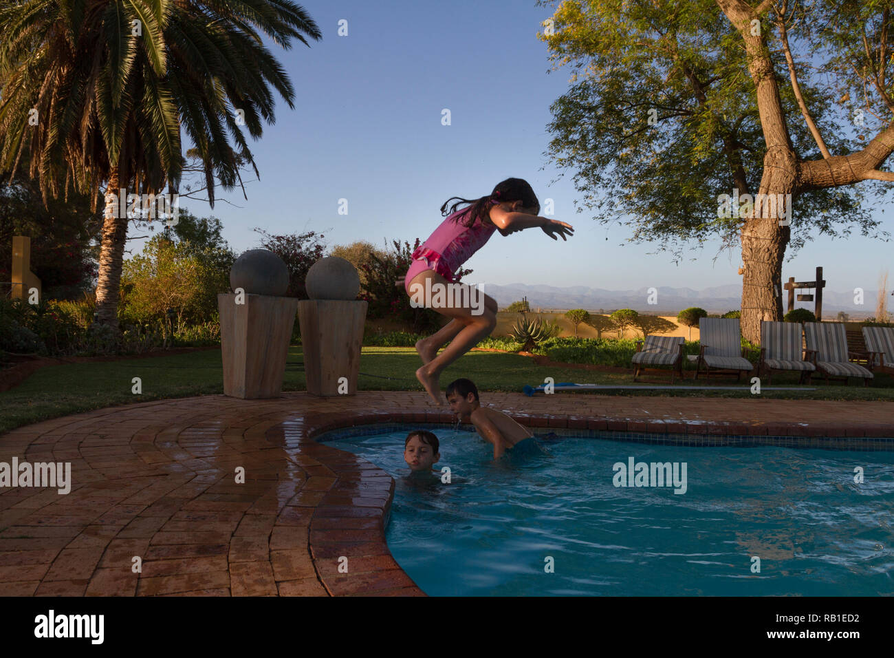 Young girl jumps in the pool, cannonballing. Stock Photo