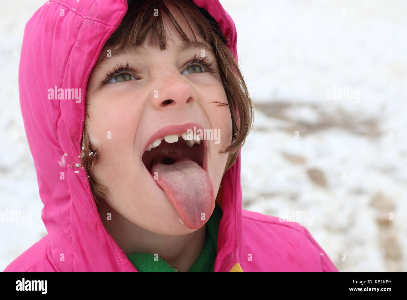 Portrait of a young girl in the snow trying to catch a snowflake on her tongue Stock Photo