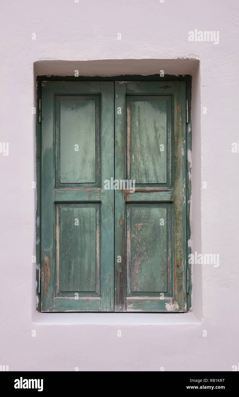 Old fashioned worn window with green wooden shutters, closed, on ...