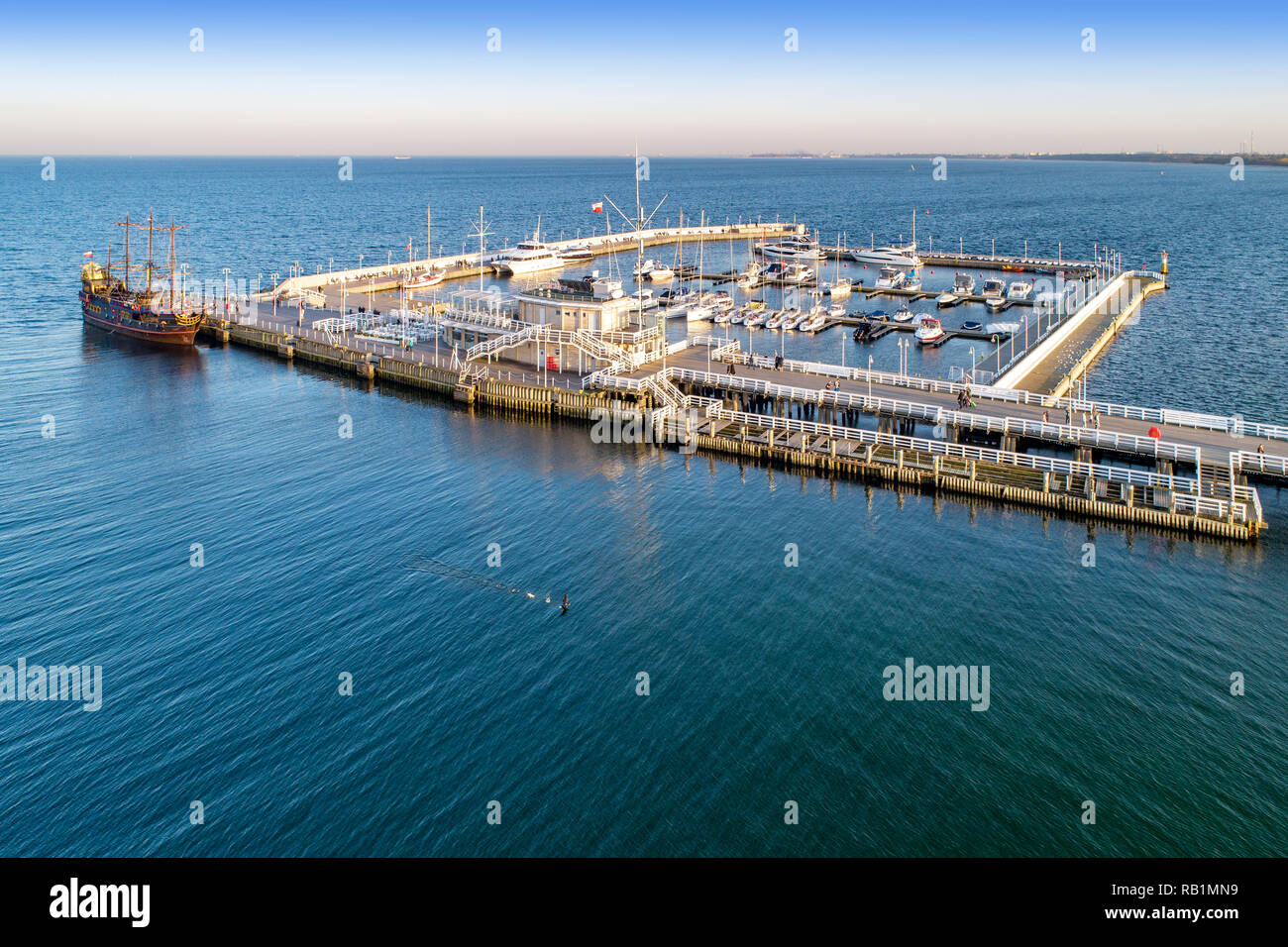 Wooden pier, called Molo, with harbor, pirate tourist ship and marina with yachts in Sopot resort near Gdansk in Poland in sunset light. Aerial view Stock Photo