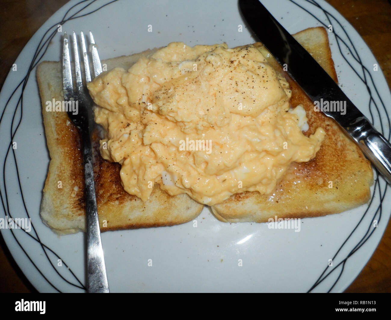 A popular English breakfast of Scrambled egg on two slices of buttered toast. Stock Photo