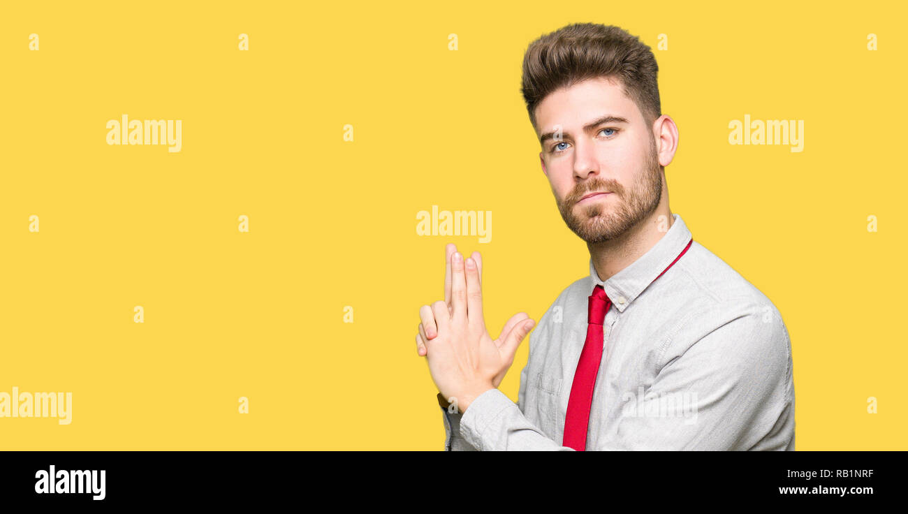 Young handsome business man Holding symbolic gun with hand gesture, playing killing shooting weapons, angry face Stock Photo