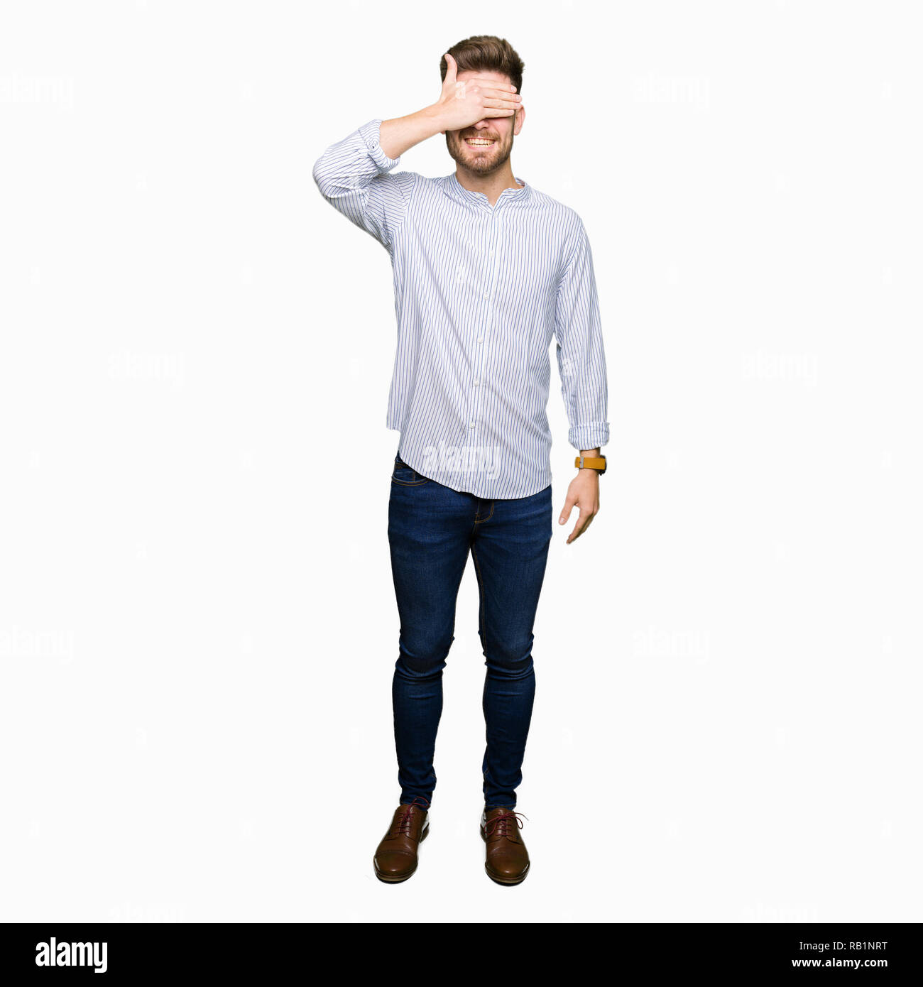 Young handsome man smiling and laughing with hand on face covering eyes ...