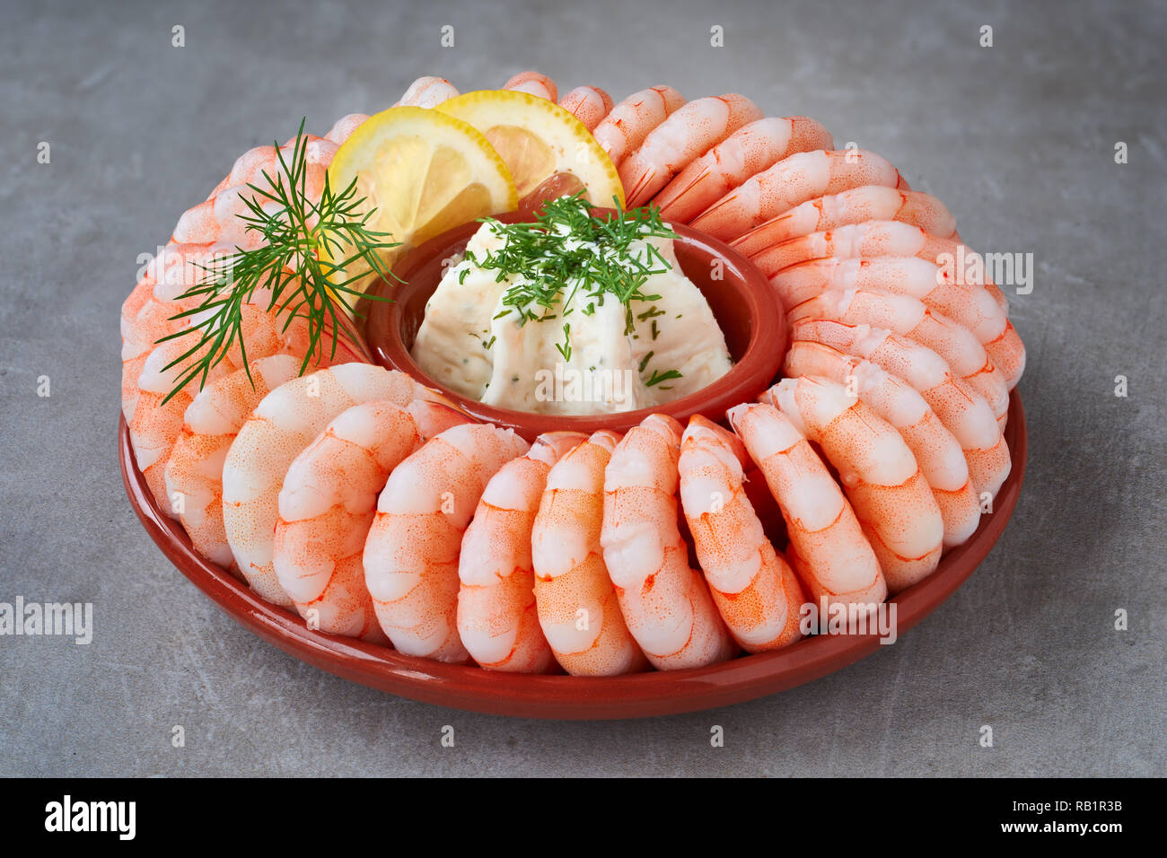 Close-up on shrimp ring with fresh cheese, dill and lemon on light concrete background Stock Photo