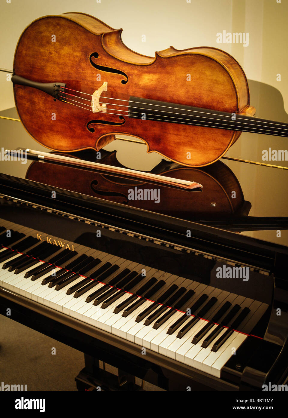 Cello and bow on grand piano with cream background Stock Photo - Alamy