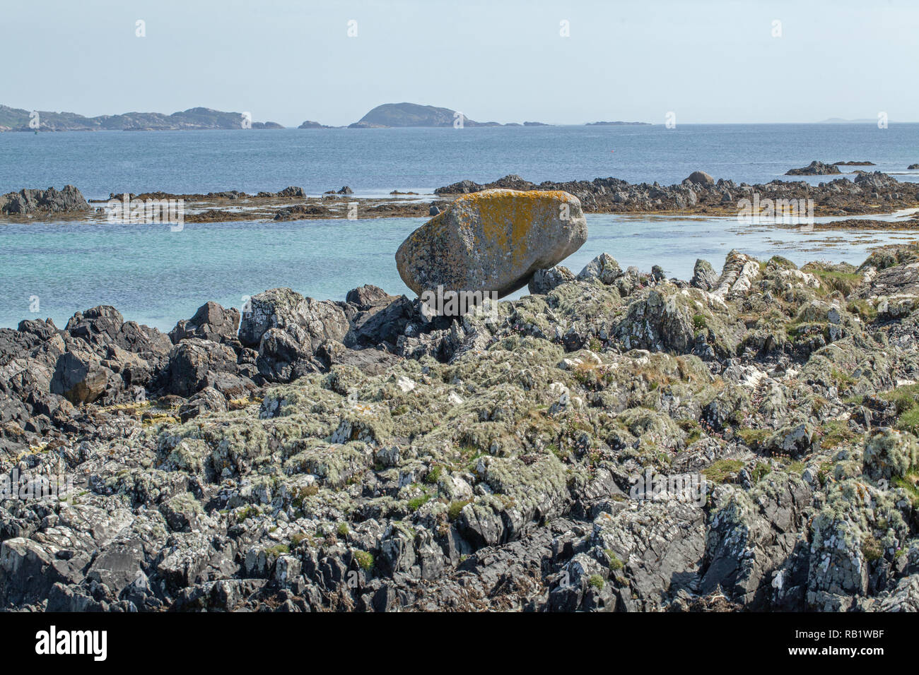Moraine deposited, large boulder, granite, rock, stone, deposited, foreground. The Isle of Iona, Port Beag Na Sligineach, Sound of Iona, Inner Hebrides. Mull on Horizon. West Coast of Scotland. Stock Photo