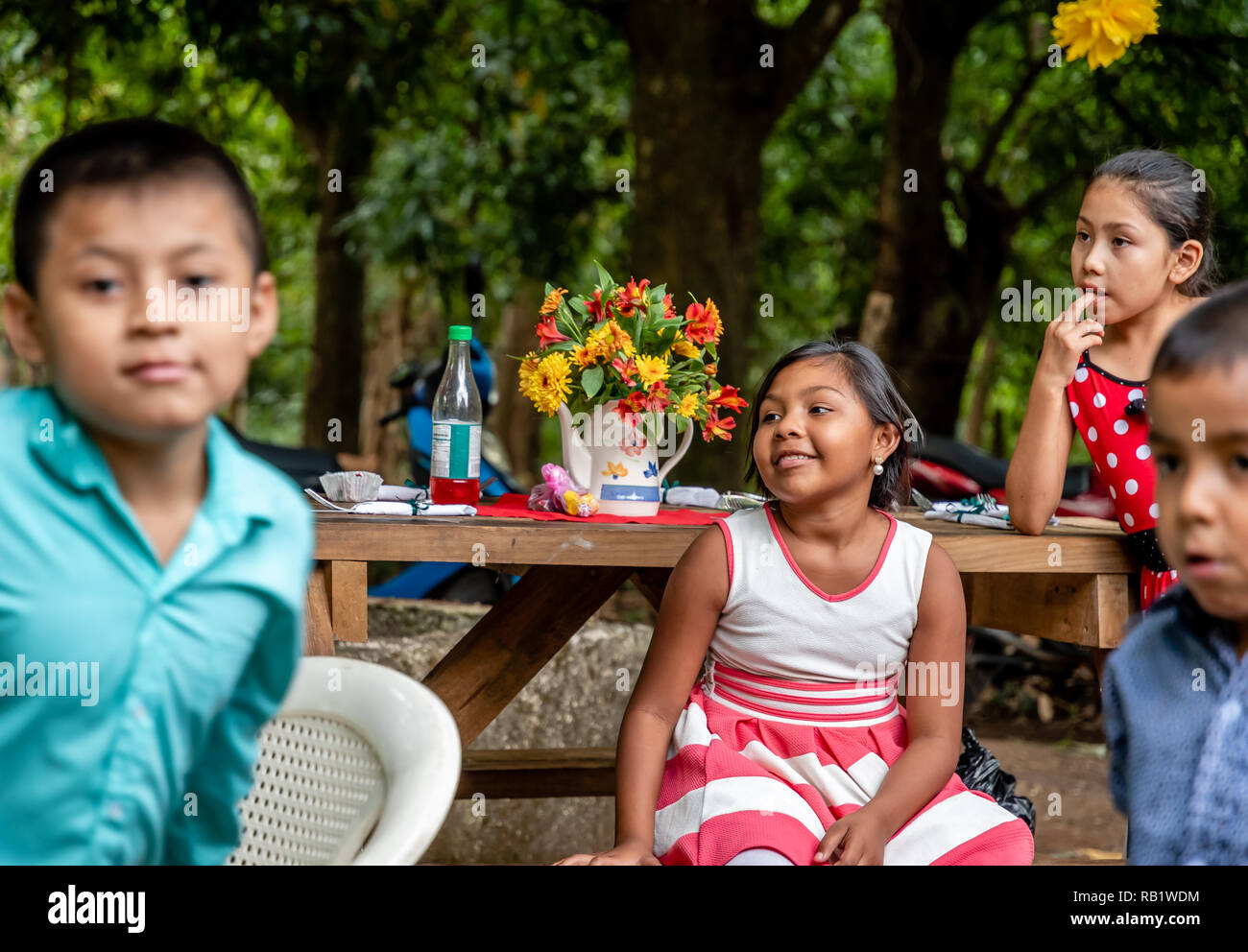 latin kids sitting at picnic table at party in Guatemala Stock Photo