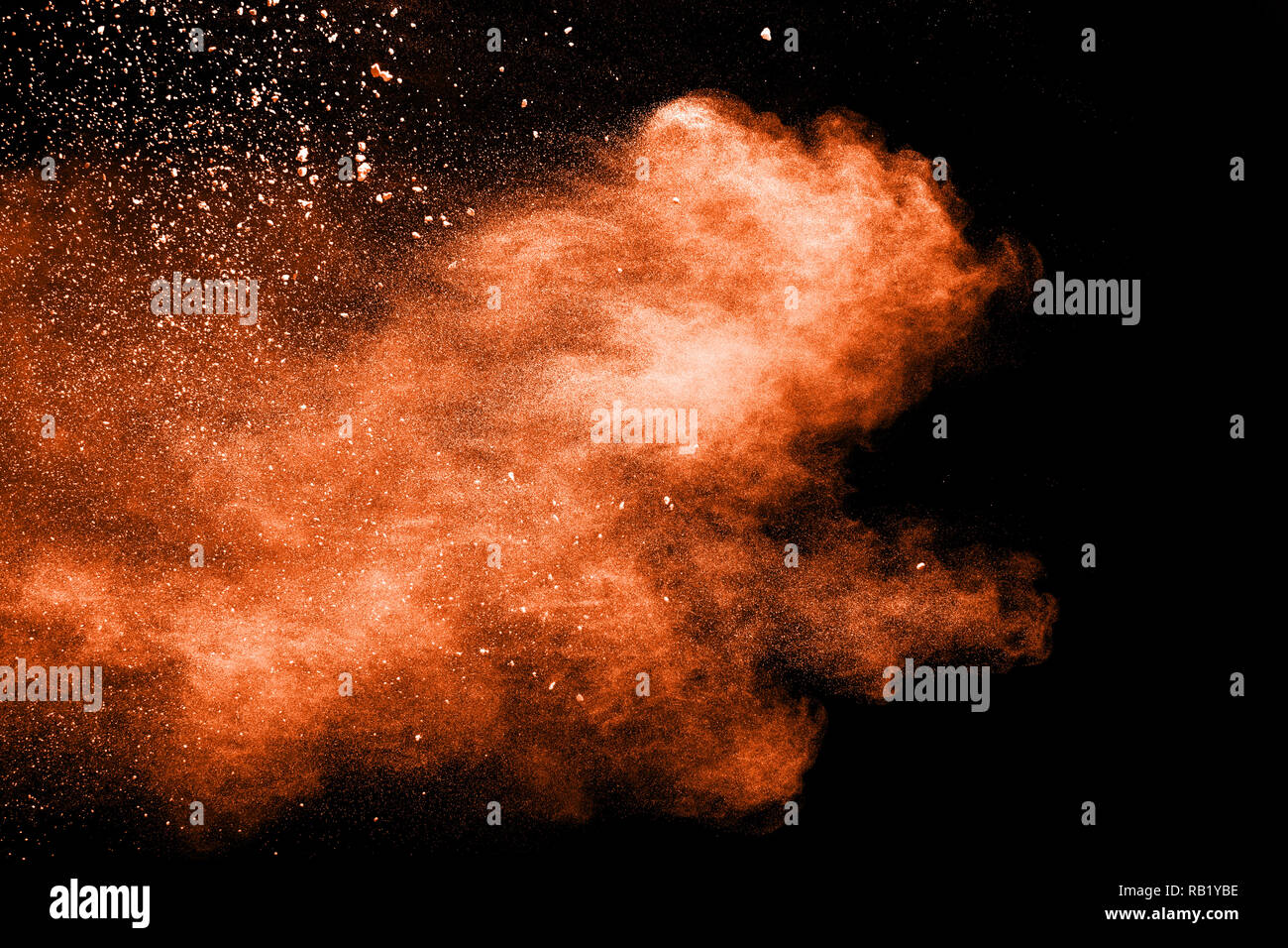 Abstract explosion of orange dust on black background. Freeze motion of