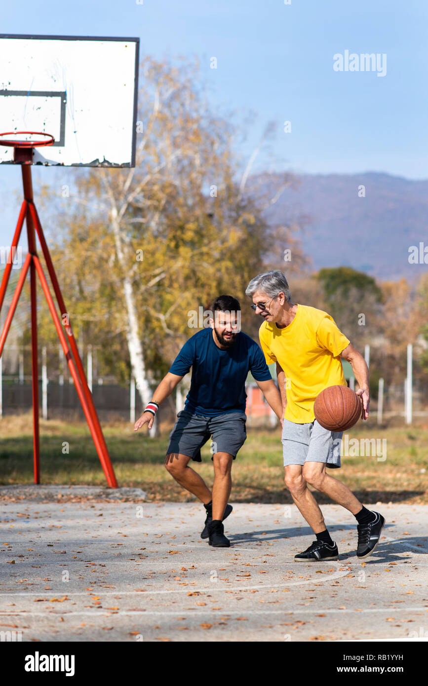 Father and son playing basketball in the park Stock Photo