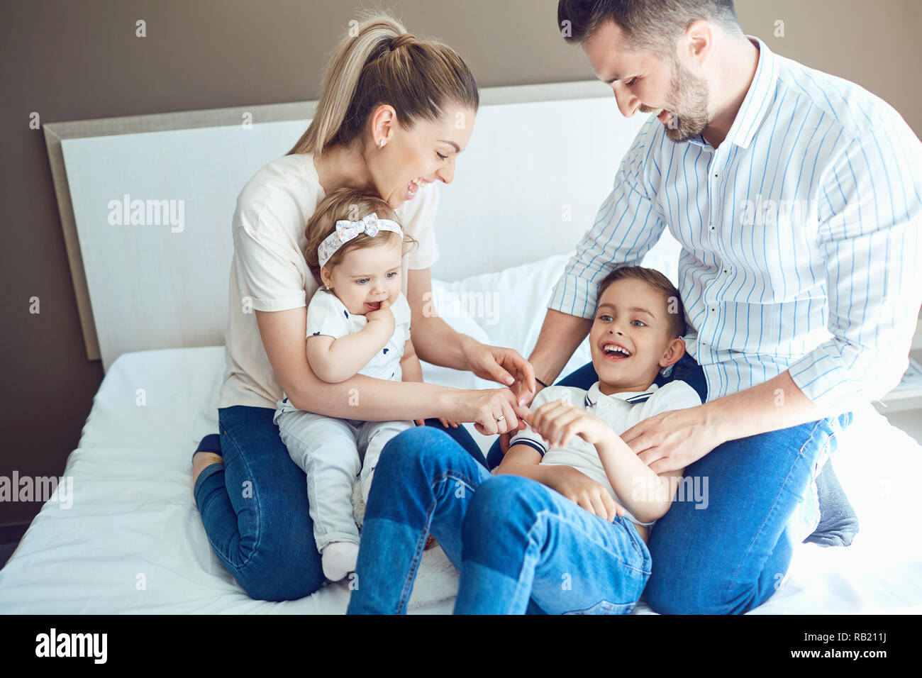 Happy family having fun playing lying on the bed. Stock Photo