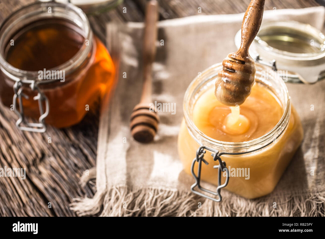 Honey in jars and  dipper on rustic oak table. Stock Photo