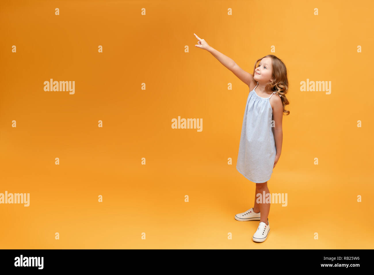 Little child girl shows hand up, yellow background Stock Photo