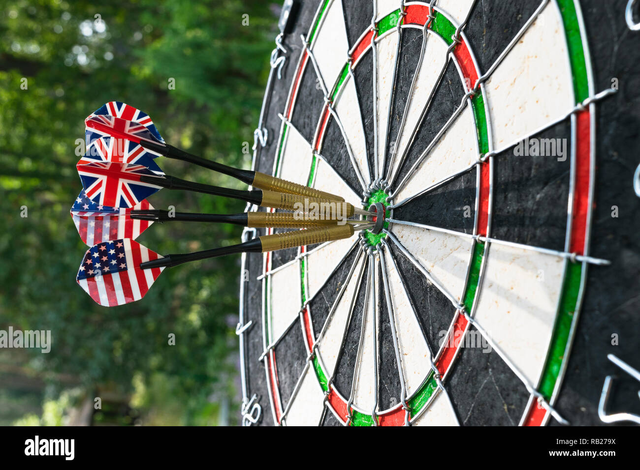 Metal darts have hit the red bullseye on a dart board. Darts Game. Darts arrow in the target center darts in bull's eye close up. Success hitting Stock Photo