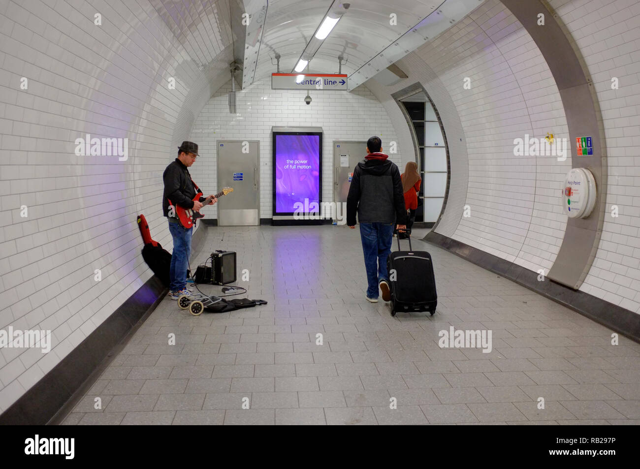 a busker on the london underground entertains passing passengers in one of the tunnels at tottenham court road tube station Stock Photo