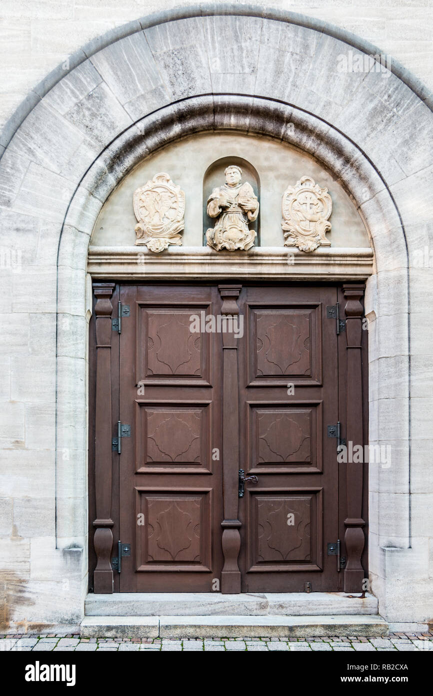 Old door of a historical building with statues and coats of arms made