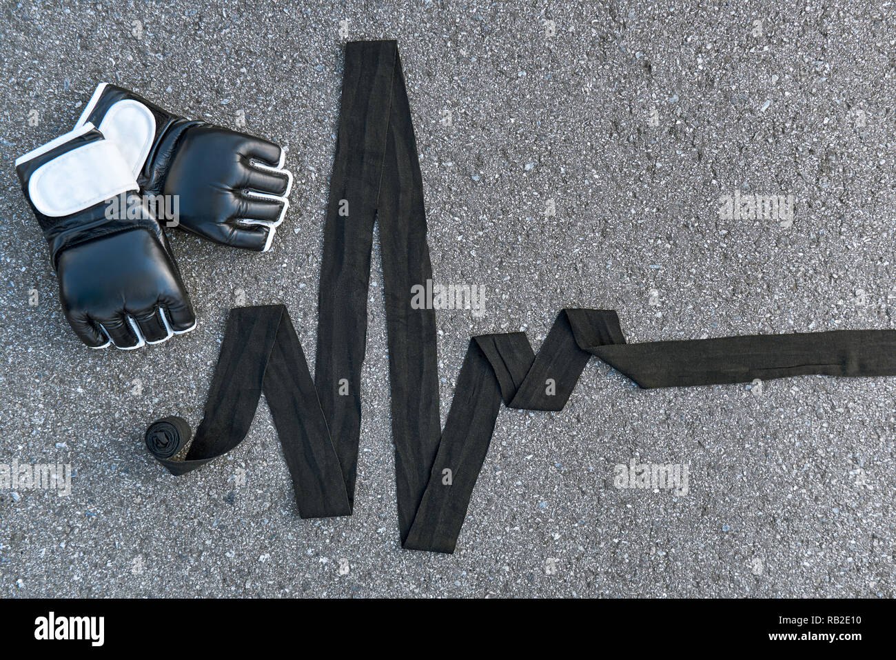 High pulse rate. Close-up of sports boxing gloves with boxing bandages at the asphalt background Stock Photo