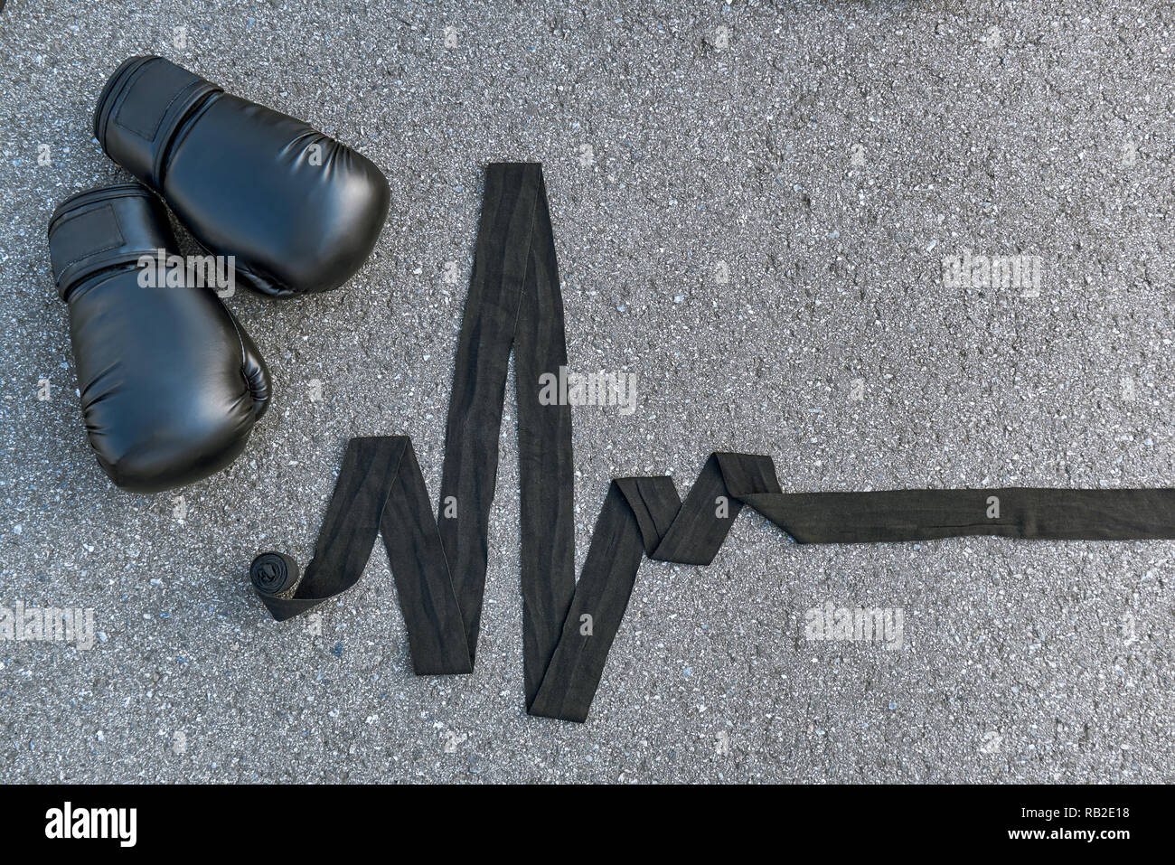 High pulse rate. Close-up of sports boxing gloves with boxing bandages at the asphalt background Stock Photo