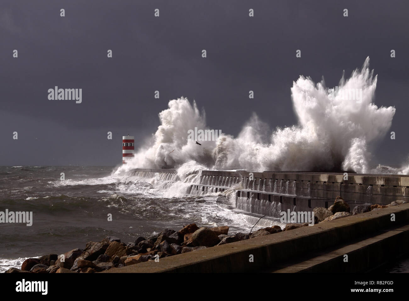 Big stormy waves over a pier and lighthouse, Porto, Portugal Stock Photo