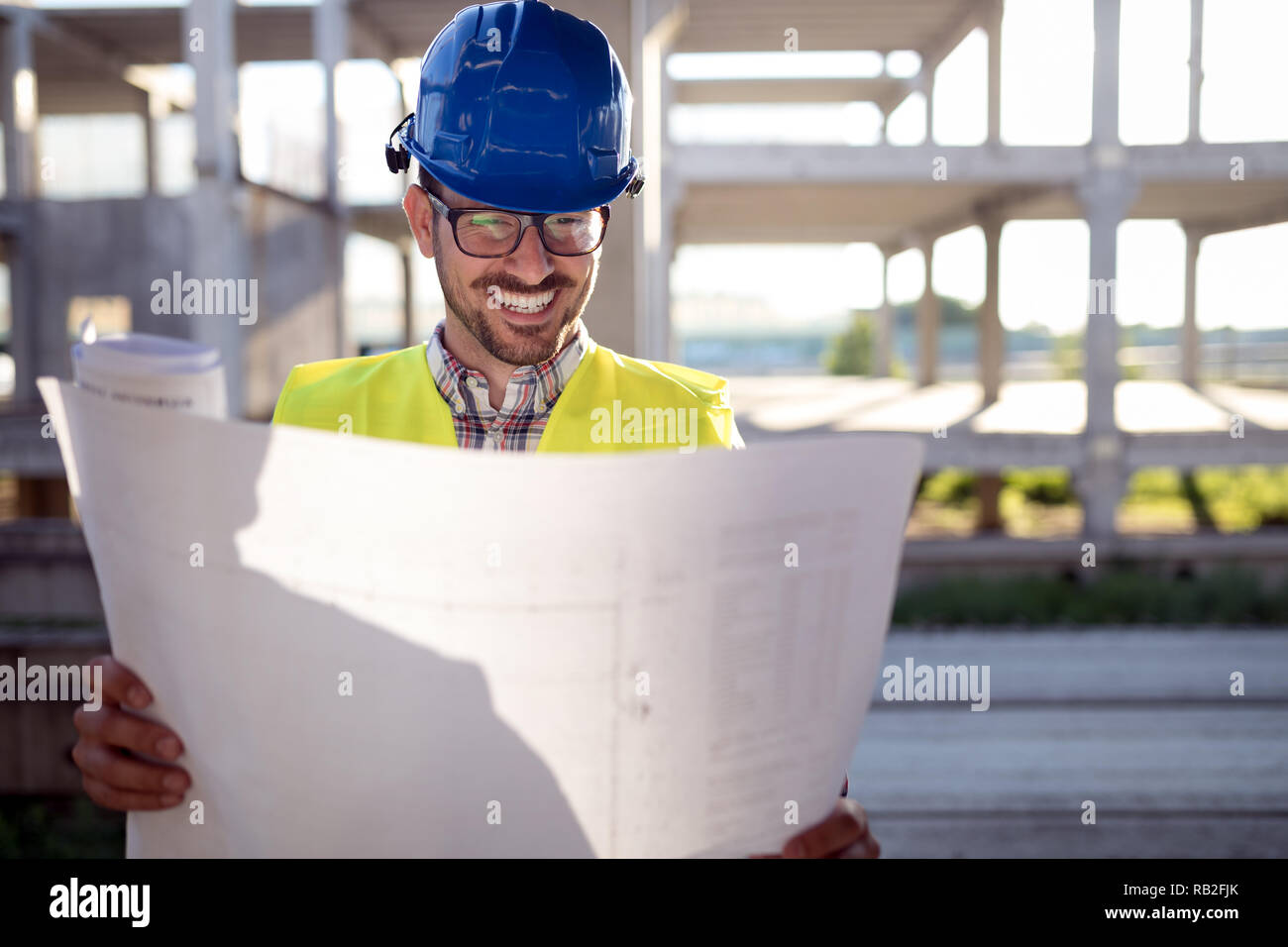 Engineer working on construction site and holding blueprint Stock Photo ...