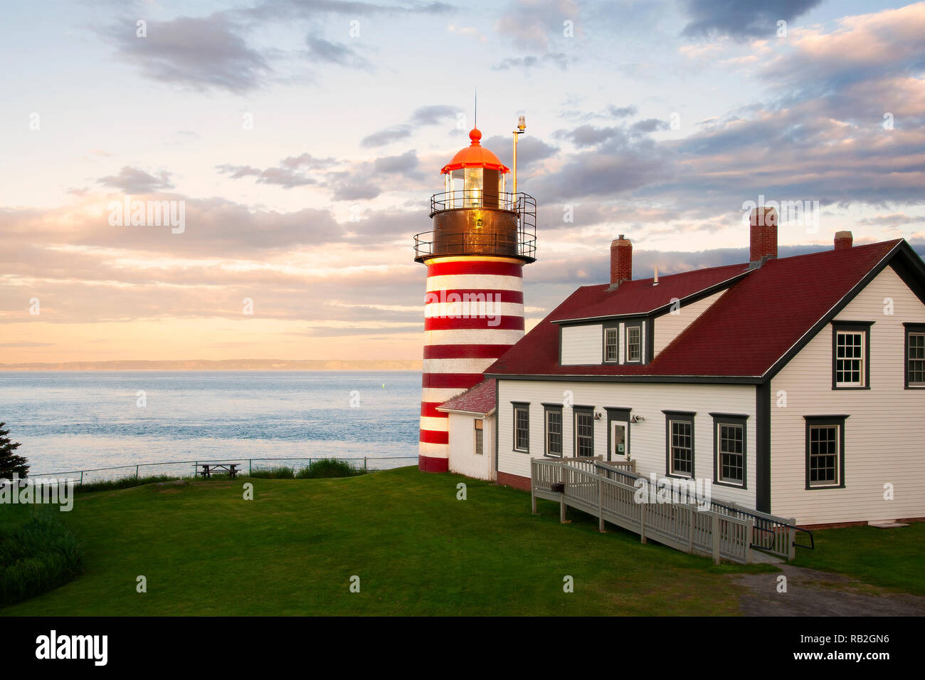 Sunset by West Quoddy Head lighthouse, with its red and white stripes, referred to as the “candy cane” lighthouse, in down east Maine, in New England. Stock Photo
