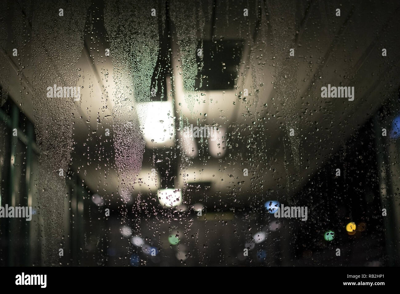 Abstract moody dew view on window with lights in commuter train transit area winter evening in Stockholm, Sweden. Stock Photo