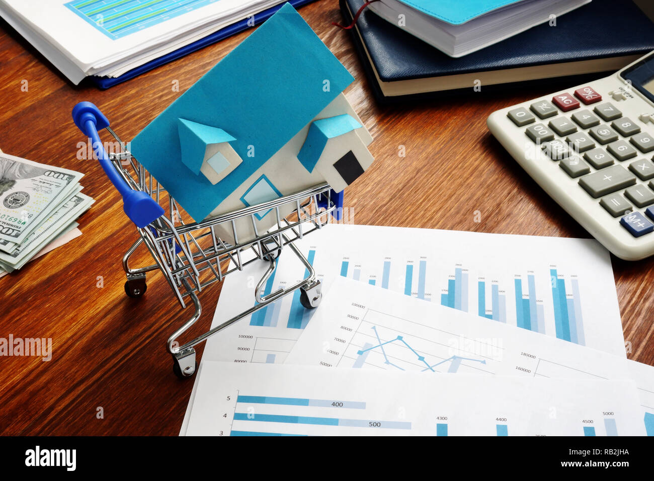 Real estate investment trusts REITs. Shopping cart and model of house. Stock Photo