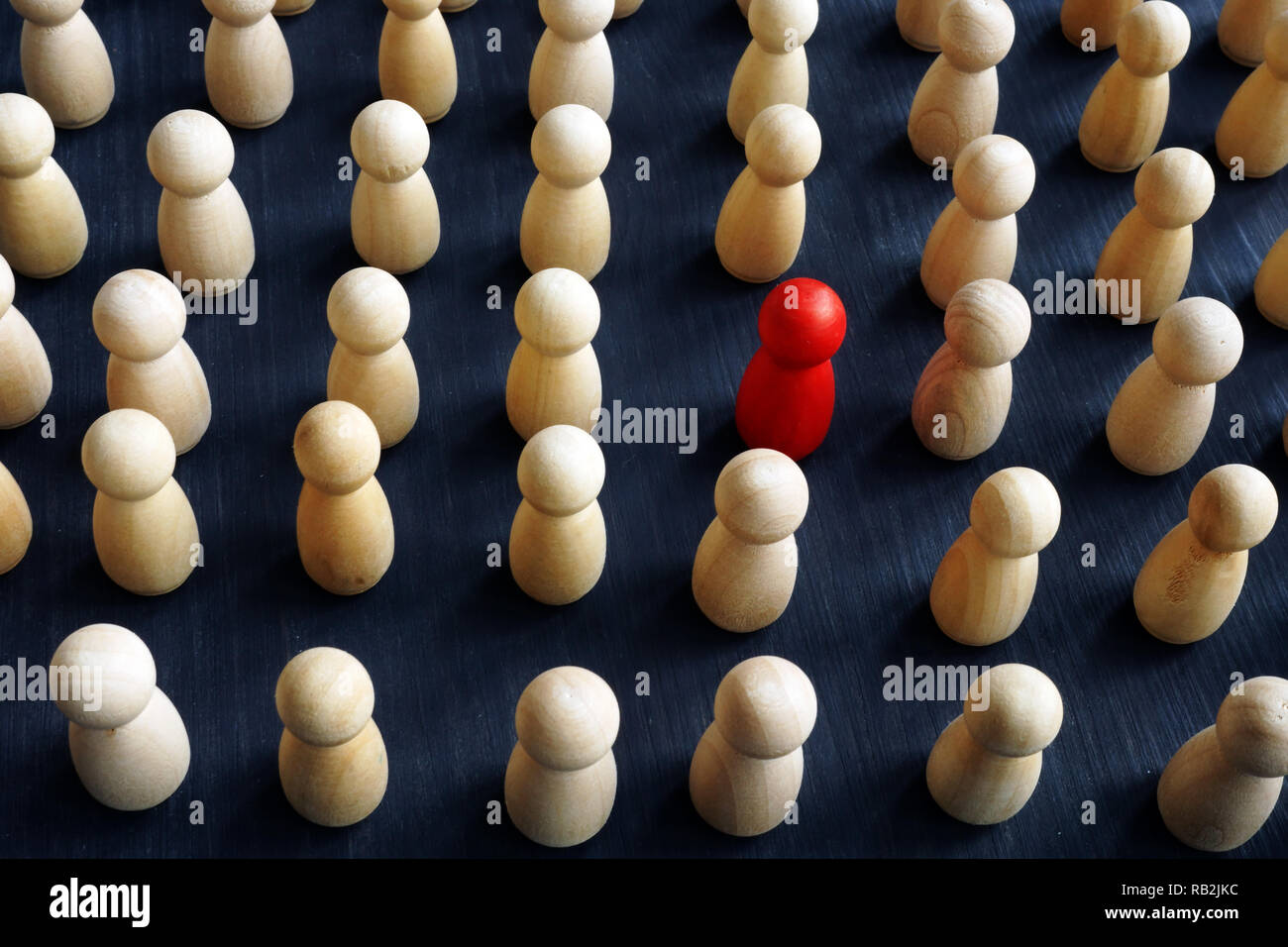 Unique, individual and think differently. Crowd of wooden figures and red one. Stock Photo