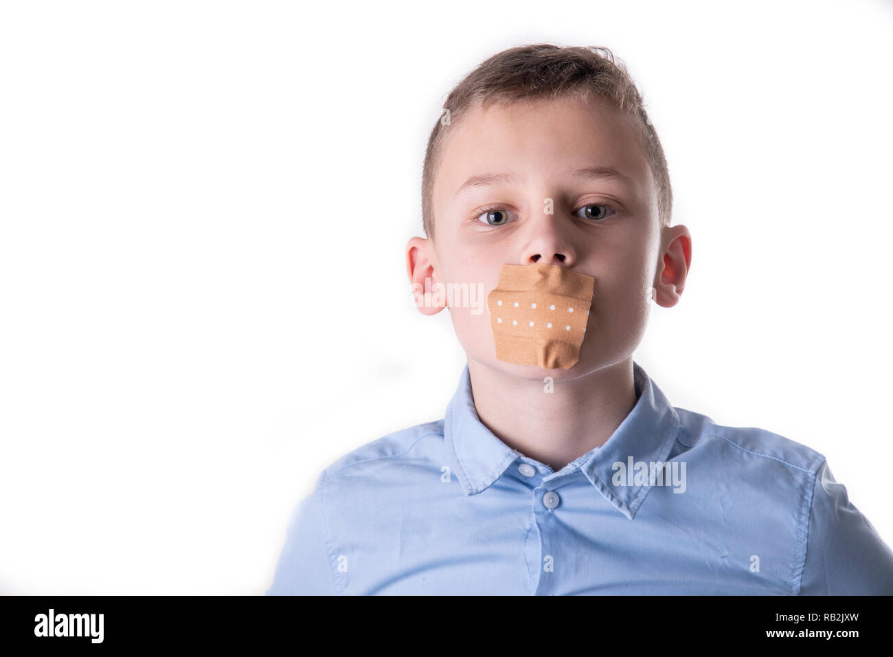 Boy can't talk with a BandAid over his mouth in blue shirt Stock Photo