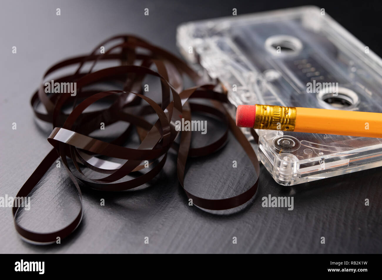 Audio cassette and pencil on a black table. Old data carrier. Dark background Stock
