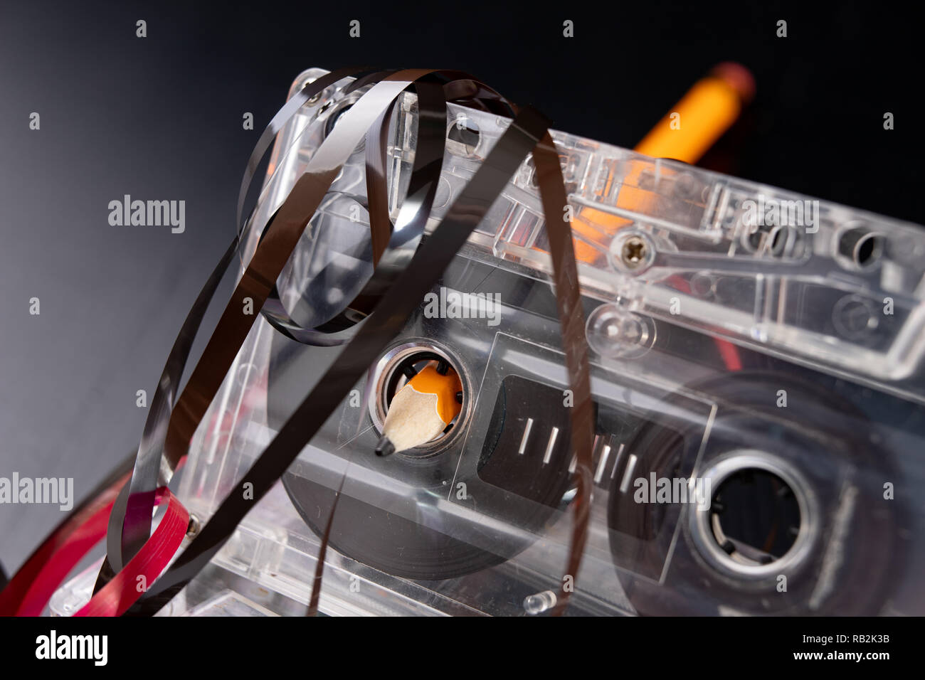 Audio cassette and pencil on a black table. Old data carrier. Dark background Stock