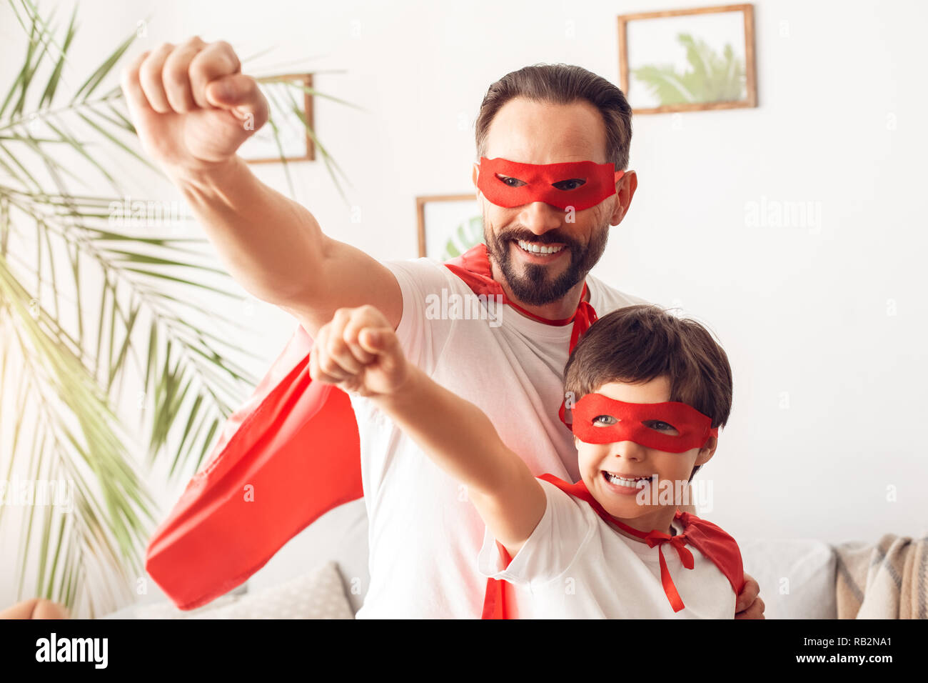Father and son in superheroe costumes at home standing hands forward confident superpowers Stock Photo