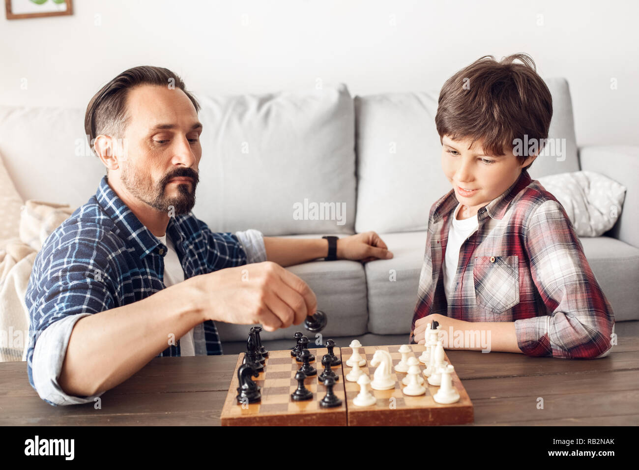 Father and little son at home sitting at table playing chess dad moving  piece concentrated Stock Photo - Alamy
