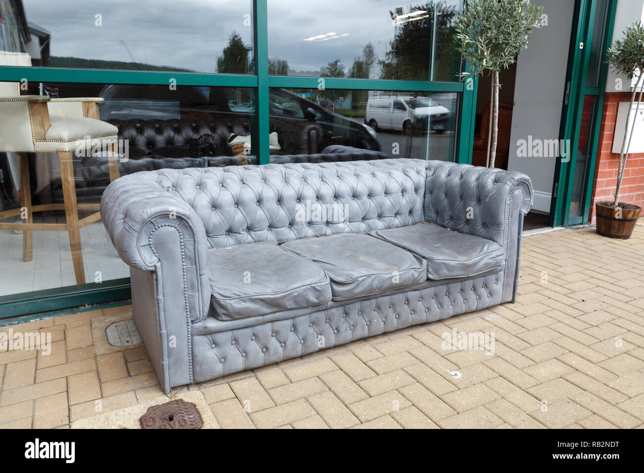grey couch made of stone in front of a furniture store, UK Stock Photo