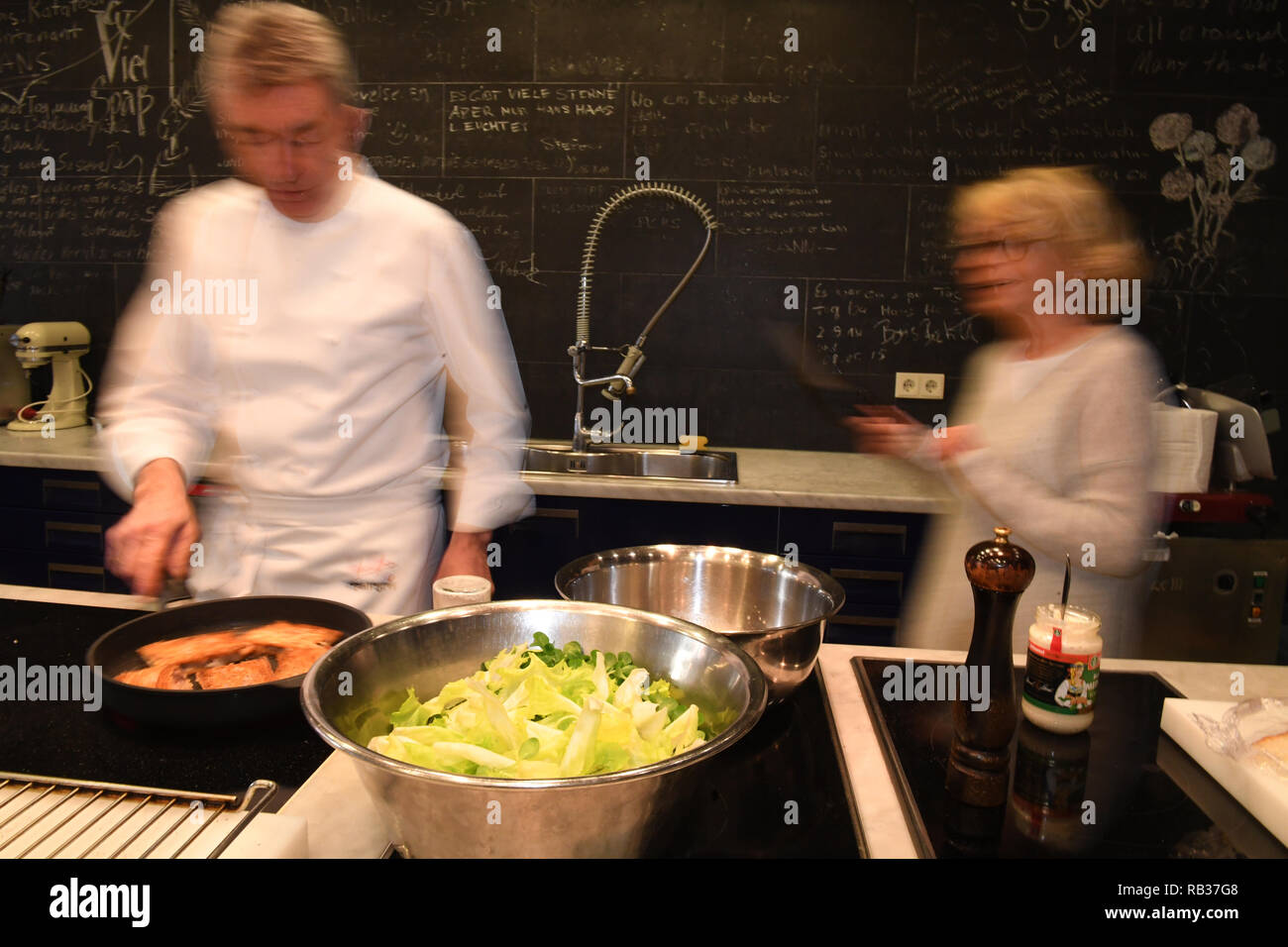 03 January 2019, Bavaria, München: dpa exclusive: The actress Gisela Schneeberger (r) and the star chef Hans Haas (both long exposure) cook on the occasion of the broadcast of the ZDF two-parter 'Bier Royal' in the Hans Haas cooking school 'Kalbskopf in Ciabatta gebraten auf Endiviensalat'. Photo: Felix Hörhager/dpa Stock Photo