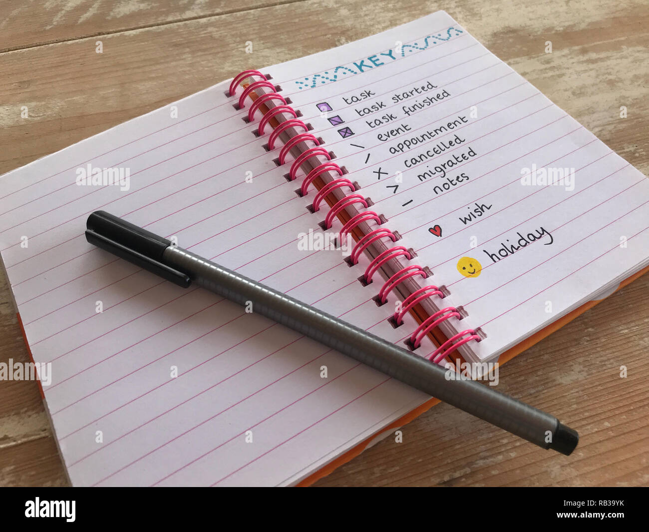 Open bullet journal and black pen on a wooden desktop Stock Photo