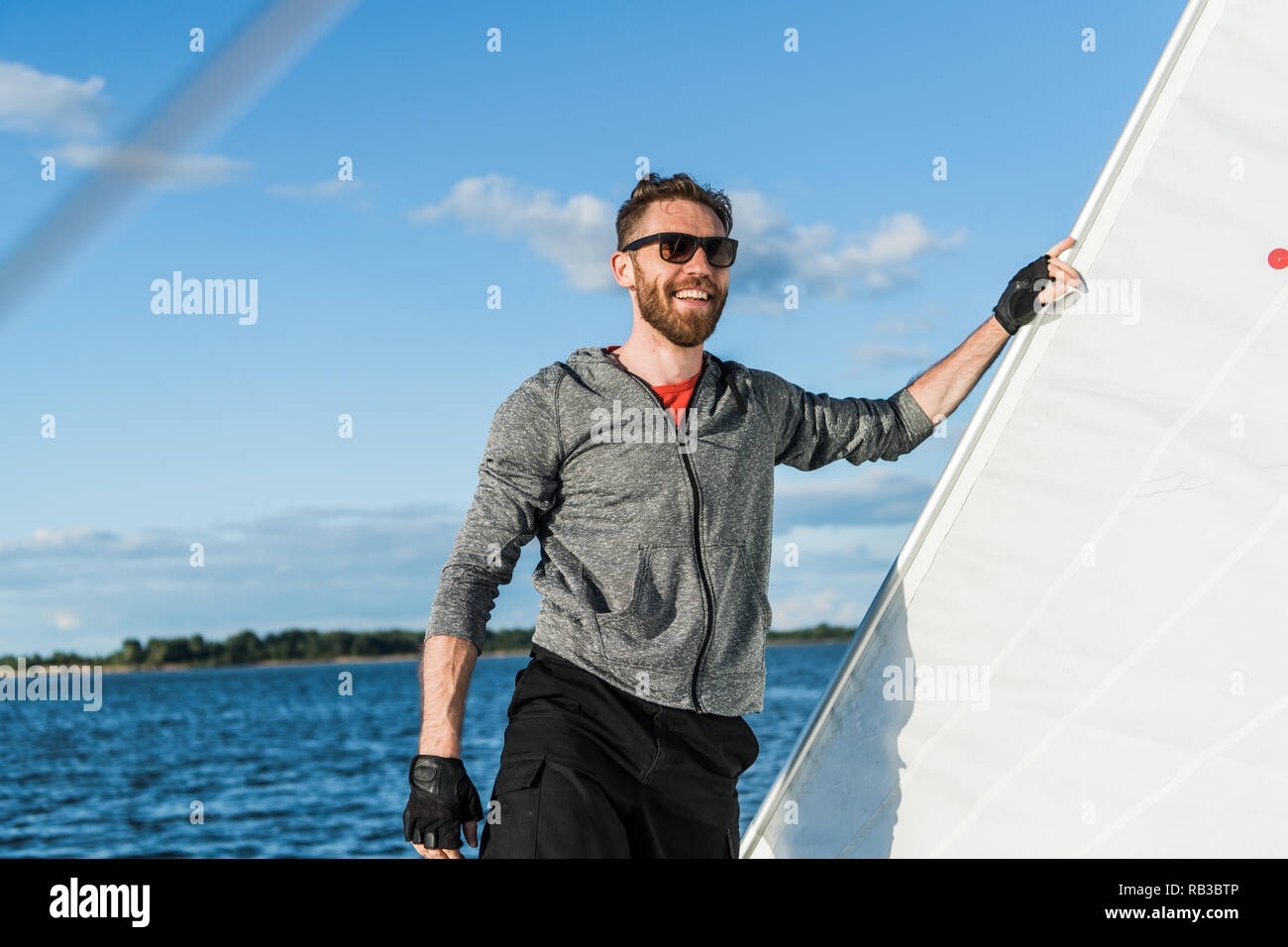 A handsome bearded man in sunglasses on a boat on a river or lake. Beautiful happy guy swimming in a boat on a autumn sunny day feeling free enjoying life Stock Photo