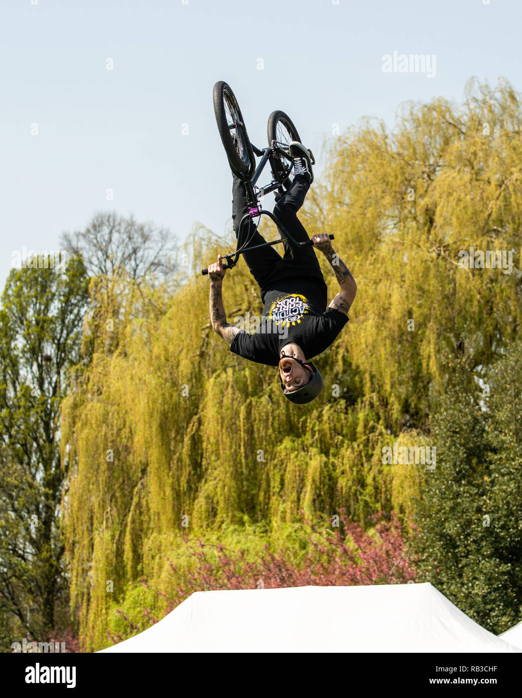BMX trick cyclist mid somersault, high in the air, performing at a country fair Stock Photo
