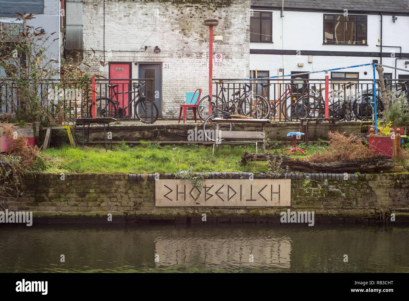 Canal side sign with rune like lettering Shoreditch, busy scene with bikes by railings Stock Photo