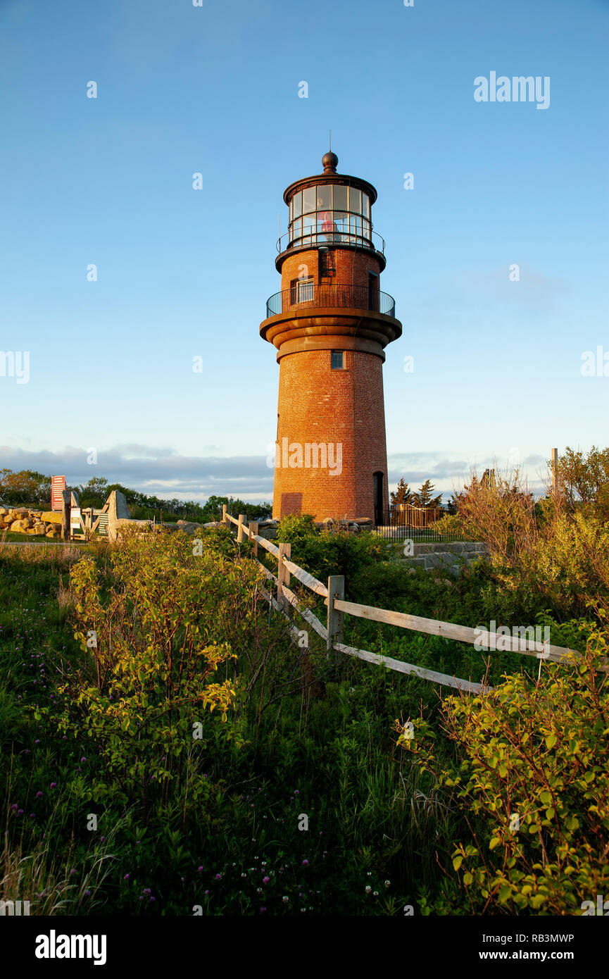 Setting sun illuminates the brick tower of Aquinnah lighthouse on the island of Martha’s Vineyard in Massachusetts. Stock Photo