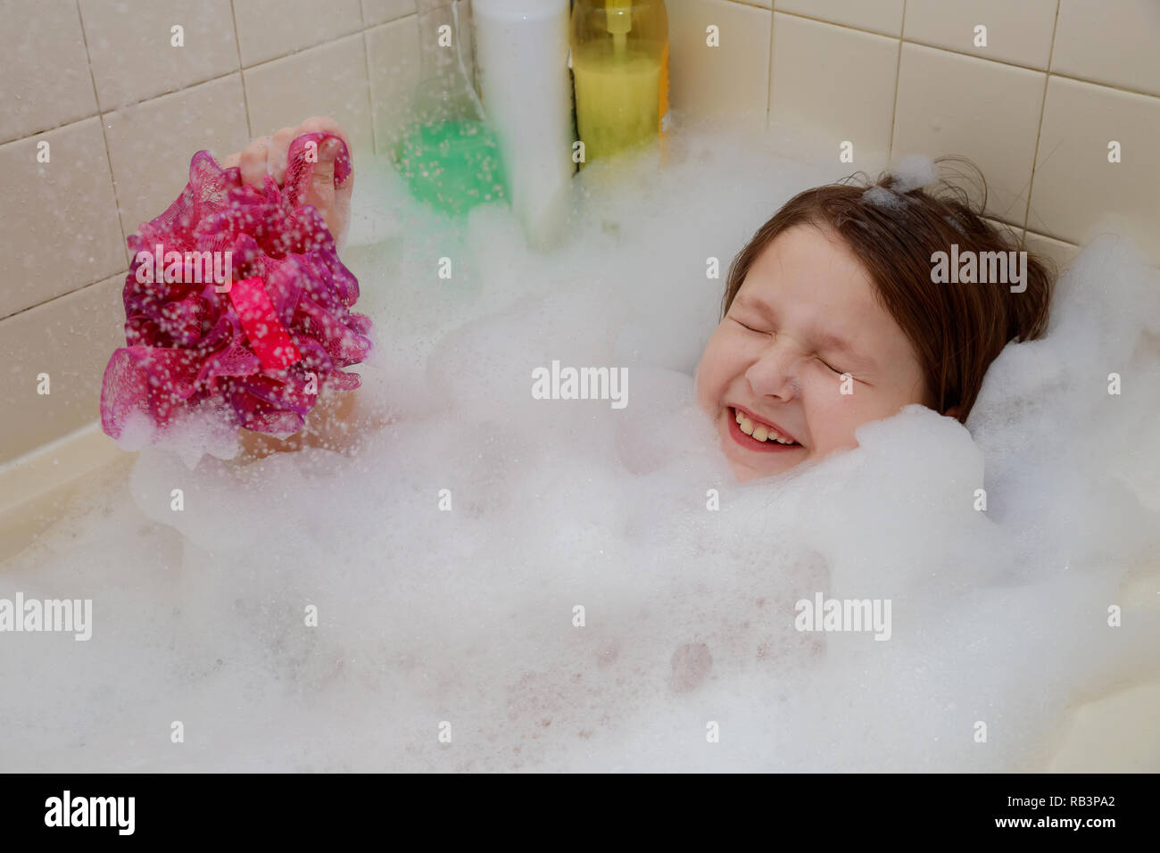 Baby little girl sitting up to their necks in bubbles in the bath have